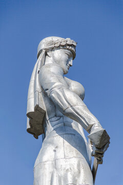 View of the Mother of Georgia statue standing tall against a vibrant blue sky, holding a sword and wine cup, embodying strength and hospitality, Mother of Georgia, Tbilisi, Georgia.