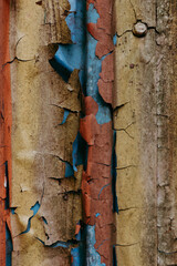 Weathered metal surface with peeling paint in vibrant colors. Close-up of a textured metal surface with layers of yellow, brown, blue peeling paint in various colors, showcasing age and decay.