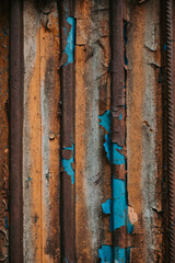 Weathered metal surface with peeling paint in vibrant colors. Close-up of a textured metal surface with layers of yellow, brown, blue peeling paint in various colors, showcasing age and decay.