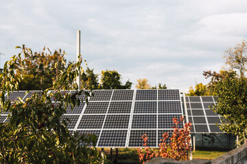 Solar panels installed on a rooftop, generating clean energy. A view of solar panels on a rooftop, surrounded by trees, under a cloudy sky, promoting renewable energy and sustainability.