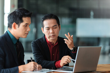 Asian businessmen collaborating on a new project, analyzing data and discussing strategy in a modern office environment