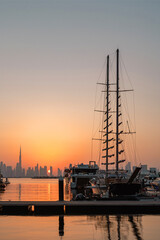 Sunset over Dubai skyline with Burj Khalifa view from Dubai Creek Harbour Marina, yachts and modern cityscape