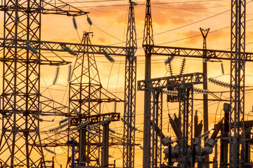 Electricity distribution infrastructure silhouetted against a vibrant sunset sky
