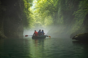 Kayaking trip in a misty forest river surrounded by green trees on a calm summer day in the Martvili Canyon in Georgia