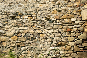 Old stone wall displaying intricate patterns and natural colors in bright sunlight in an outdoor setting