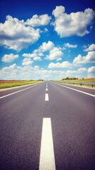 Long straight road under a bright blue sky with fluffy white clouds on a sunny day in the countryside