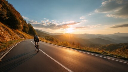 Man cyclist on road bike riding on mountain road. Scenic autumn landscape with setting sun and mountains. Sport activity.