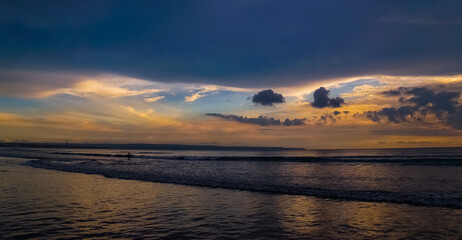 A man fishing on Bali Kuta beach at sunset on a cloudy day