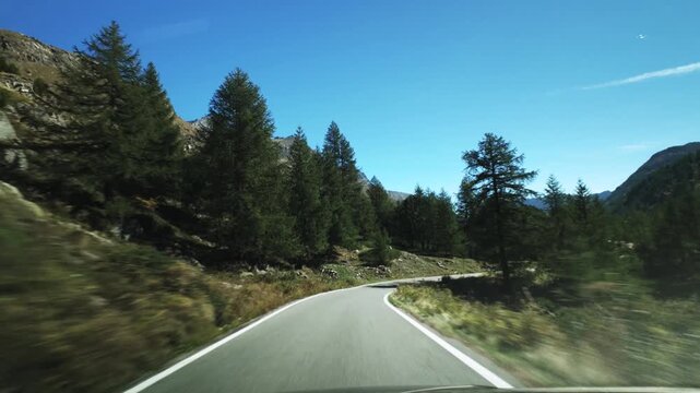 Driving a car on an empty curved mountain road in the Alps on a sunny day. Road trip vacation adventure video. First person view.
