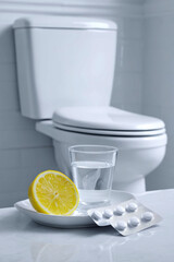 Toilet and Medication with Lemon – Conceptual Image for Nausea, Food Poisoning or Hangover Detox