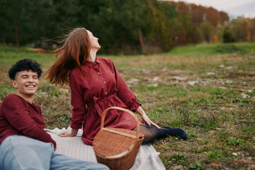Young couple enjoying a candid picnic on a grassy meadow with a wicker basket and blanket, captured in an authentic moment conveying natural connection and credibility.