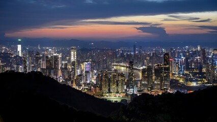 Naklejka premium Chongqing China cityscape at sunset with mountain silhouettes and illuminated skyscrapers in southwestern China