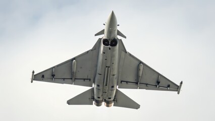 modern air combat uk Military jet flying overhead against a cloudy sky.