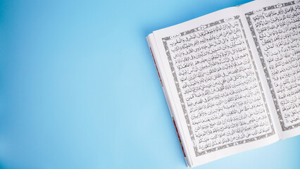 Obraz premium Open Quran book on blue background with copy space