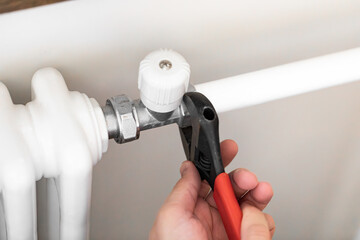 Plumber man is blocking repairs radiators of heating battery in apartment tap.