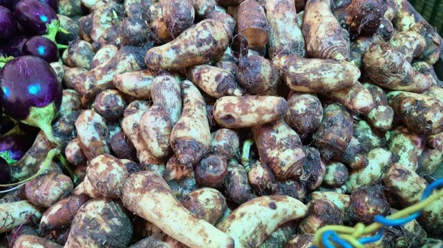 Raw arbi, also known as taro root, is displayed for sale at a shop, showcasing fresh vegetables available.