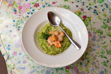 spinach risotto with shrimp and scallops on a white plate, top view
