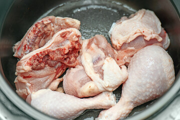 Raw chicken drumsticks in a pot sprinkled with salt, beginning the cooking process