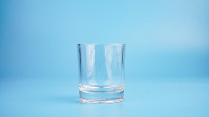 An empty glass cup on a blue background.