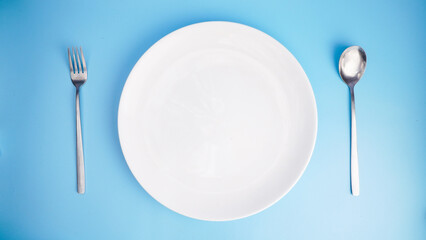 Empty Plate with Fork and Spoon on Blue Background