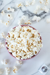 Popcorn in a bowl on white marble background. Top view.
