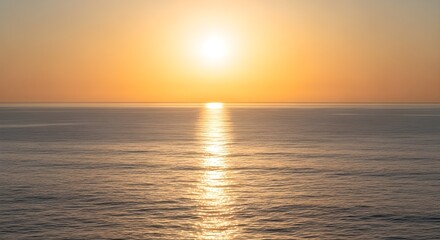 Obraz premium A breathtaking golden sunset illuminates the tranquil expanse of the ocean, casting a radiant path of light across the calm water as the day concludes in a serene display
