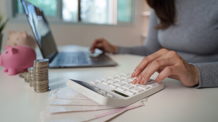 Budgeting. Woman calculating expenses with calculator and laptop.