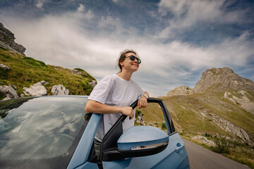 Woman with arms up having fun, car travel concept
