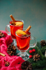 Warm winter spiced mulled wine with orange slices and cinnamon sticks on table
