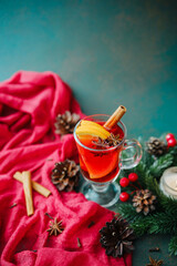 Winter spiced mulled wine drink with cinnamon stick, orange slice, star anise, pine cones, and red berries
