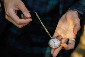 Fotobehang Vintage Close-up of a person's hands holding an antique gold pocket watch with a chain, showing vintage elegance, timeless style, and nostalgic craftsmanship in warm natural light  © halcon1