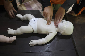 First aid training baby CPR dummy, with instructor demonstrating chest compressions. This scene depicts crucial medical skill being taught, emphasizing care and emergency preparedness for infants