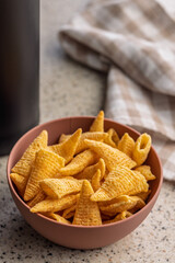 Bugles snack. Cone corn chips in bowl on kitchen table.