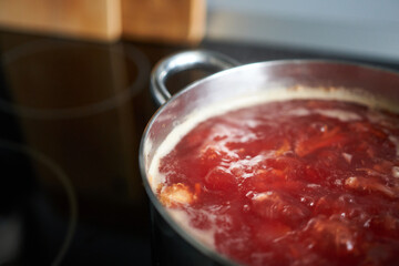 Red borscht in a pot on a stove, close-up