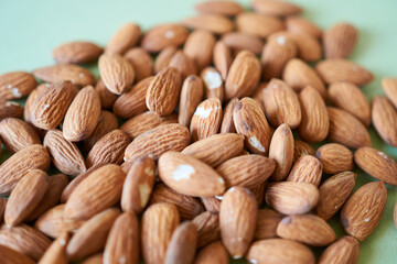 Almond nuts on green background. Healthy food concept. Closeup.