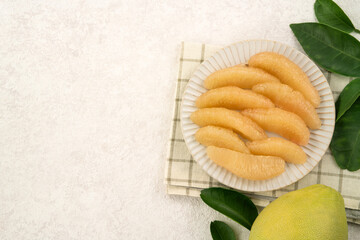 Fresh pomelo fruit with leaf on white table background.