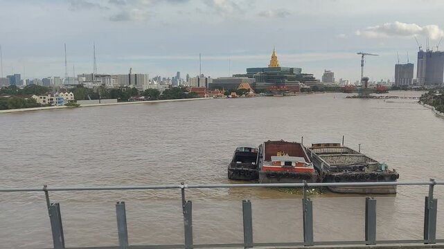 Chao Phraya River with Barges, New Thai Parliament Building and Kiak Kai Bridge Construction in Bangkok, Thailand