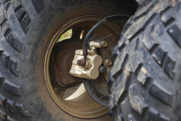 Close up of an All Terrain Vehicle ATV tire and brake caliper shows rugged texture and mechanical...