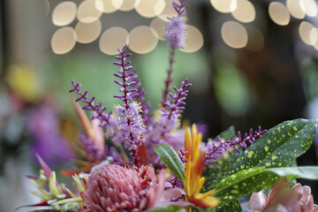 Vibrant floral arrangement radiates joy and beauty, showcasing delightful mix of colorful blooms and lush green foliage, artfully composed with soft, bokeh background evoking sense of celebration