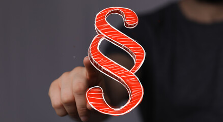 A hand points to a glowing digital paragraph symbol, representing modern legal concepts, online...