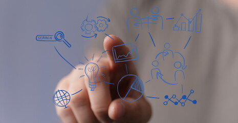 Finger pointing at an abstract digital graphic with charts, graphs, and icons representing business ideas, technology, and concepts.