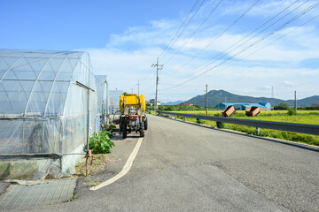 맑은 날 비닐 하우스와 농기구가 있는 농촌풍경 
