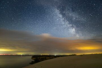 Night sky full of stars. Milky Way above the sandy dunes.