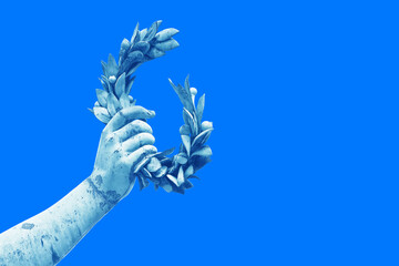 Hand holds a laurel wreath - bronze statue on colored background - Success and fame concept image