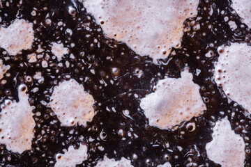 Extreme macro detail of a reactive ceramic glaze. An abstract background with a bubbly, cratered texture and organic, earthy tones for a unique design. Ultra macro photography.	