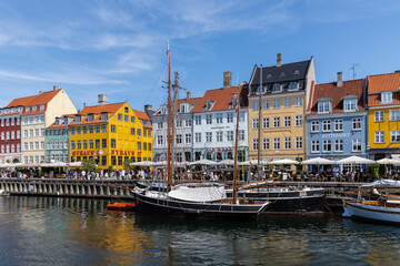 Obraz premium Copenhagen, Denmark 07-20-2025 The historic waterfront Nyhavn is a canal in the centre of Copenhagen and known for its brightly colored buildings, historic ships and the author Hans Christian Andersen