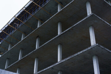 Fototapeta premium Building construction site shows concrete structure with scaffolding and bare floors on a cloudy day