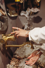 Young woman with pearl beads washes hands at a seashell-decorated washbasin in a modern setting