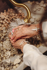 Hands cleansing with flowing water over decorative stones in a serene setting
