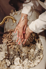Young woman with pearls washes hands in a decorative seashell washbasin
